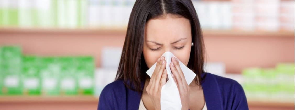 Sick woman sneezing into a tissue