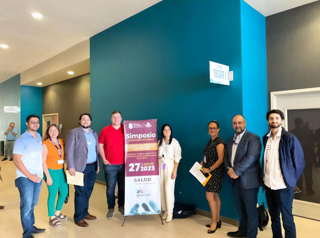 A group of men and women pose in front of a banner.