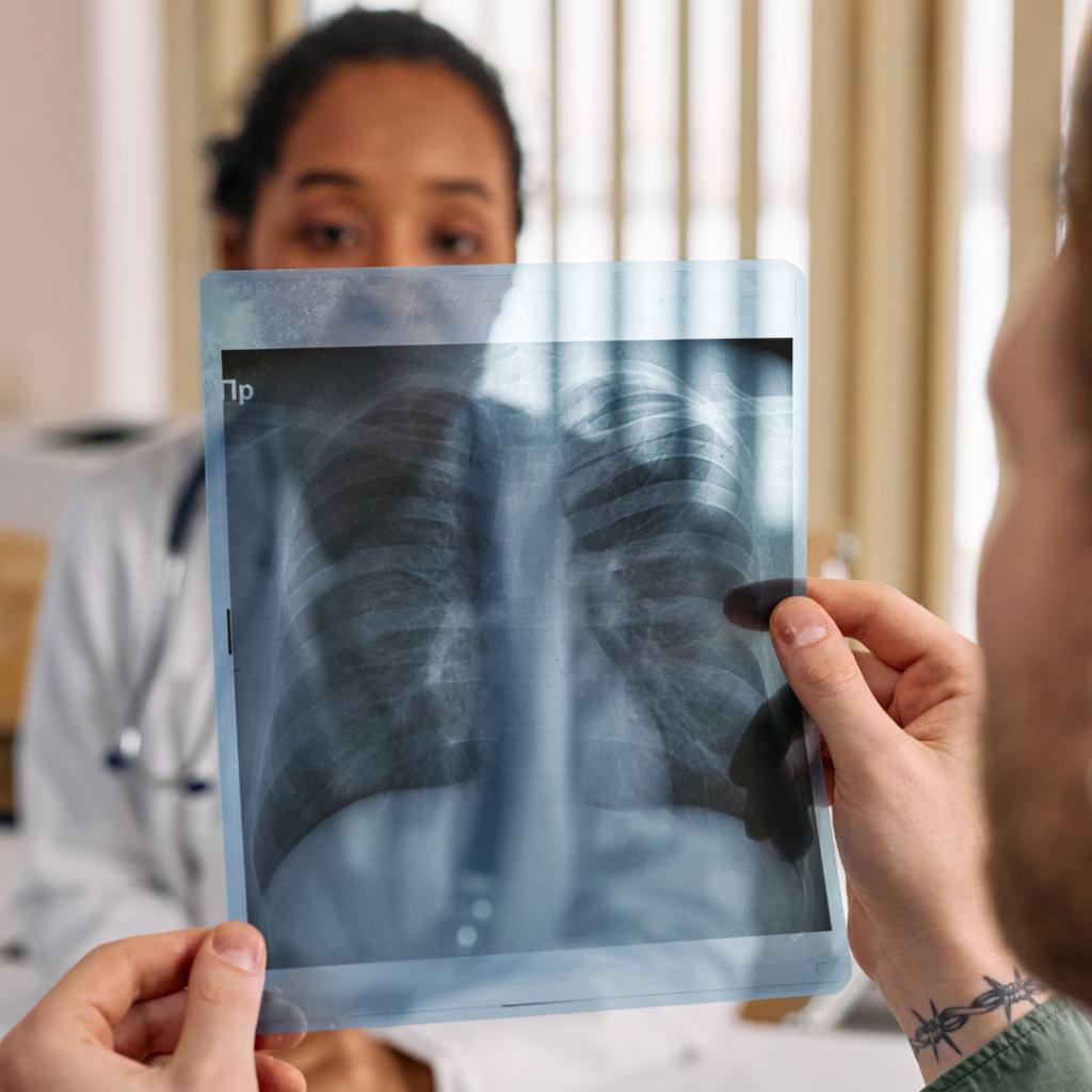 The patient is looking at the image of their lung X-ray in front of their doctor.