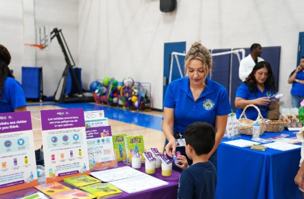 Young woman is teaching a child about healthier alternatives to drinking soda.