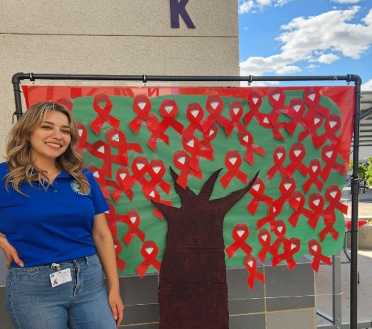 A young woman stands in front of a tree made of red ribbons, which represents the promise to stay drug-free.