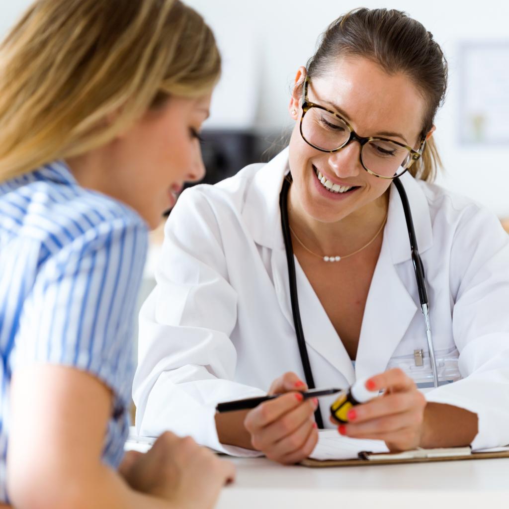 Female doctor with glasses happily consulting a female patient.