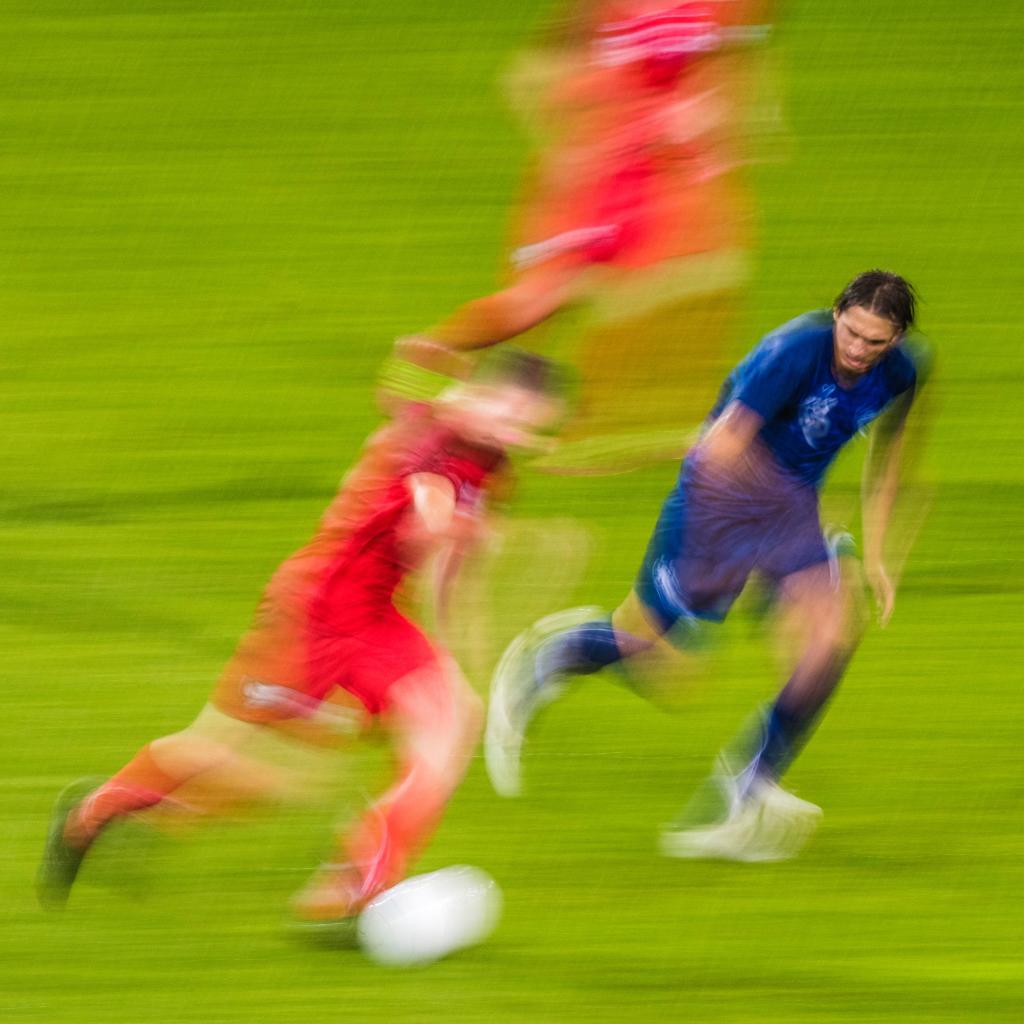 Soccer players going so fast they are blurred.