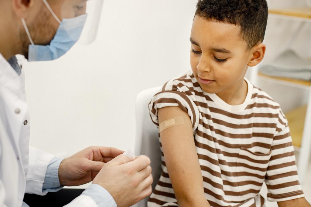Male doctor applies bandaid to a boy after vaccination