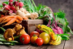 various fruits and vegetables surrounding a wooden crate.